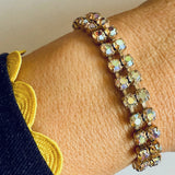 Close-up of a person's wrist wearing a sparkling bracelet on a neutral background